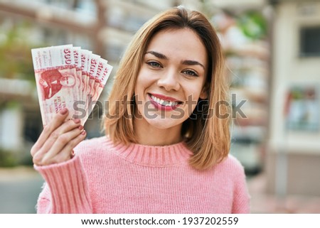 Young caucasian girl smiling happy holding iceland kronur banknotes at the city.