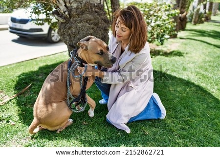 Young caucasian girl smiling happy standing with dog at the park.