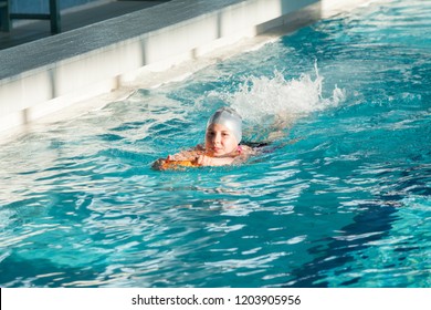 Young Caucasian girl sportive girl swimming with kickboard in pool, working legs - Powered by Shutterstock