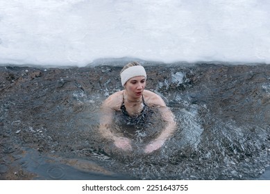 young caucasian girl swimming in cold water in winter, healthy lifestyle, tempering concept