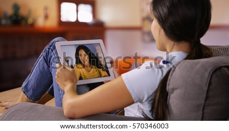 Young Caucasian girl video chats with her friend on her tablet