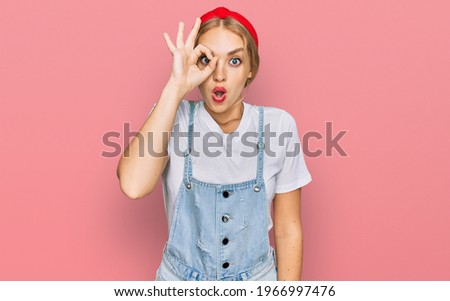 Young caucasian girl wearing casual clothes doing ok gesture shocked with surprised face, eye looking through fingers. unbelieving expression. 