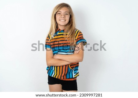 young caucasian girl wearing colorful T-shirt over white background being happy smiling and crossed arms looking confident at the camera. Positive and confident person.