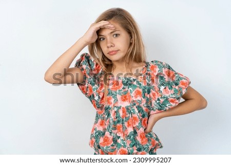 young caucasian girl wearing floral dress over white background having problems, worried and stressed holds hand on forehead.