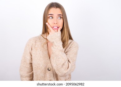 young caucasian girl wearing knitted sweater over white background Thinking worried about a question, concerned and nervous with hand on chin.