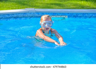 Young Caucasian Girl Wearing Swim Goggles In Above Ground Swimming Pool