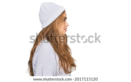 Young caucasian girl wearing wool sweater and winter cap looking to side, relax profile pose with natural face with confident smile. 