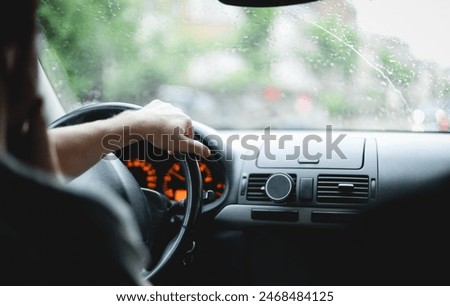 A young caucasian guy keeps his hand on the steering wheel while driving a car.