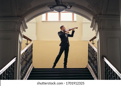 young caucasian handsome guy play violin, talented musician perform music with the use of classical instrument, wearing elegant formal suit, before concert or performance - Powered by Shutterstock