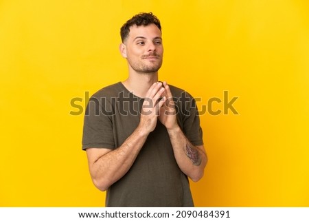 Young caucasian handsome man isolated on yellow background scheming something