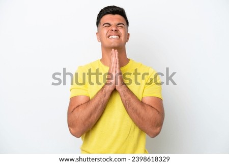 Young caucasian handsome man isolated on white background keeps palm together. Person asks for something