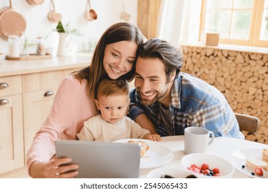 Young caucasian happy family of three with little kid child toddler infant baby watching cartoons at home on digital tablet while having breakfast. Child care and parenthood concept - Powered by Shutterstock