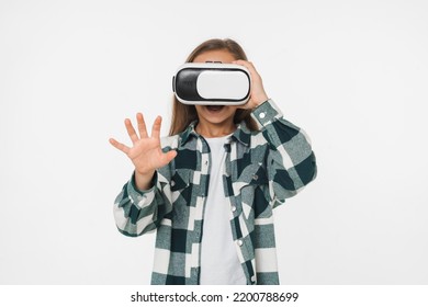 Young caucasian happy preteen teenager schoolgirl daughter wearing VR glasses, playing video games online touching copyspace isolated in white background