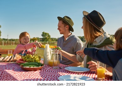 Young Caucasian Hipster Farming Family Having Lunch With Fresh Organic Products In Countryside Outdoors. Mother Giving Plate With Vegetables For Smiling Daughter. Modern Farm Lifestyle. Sunny Day