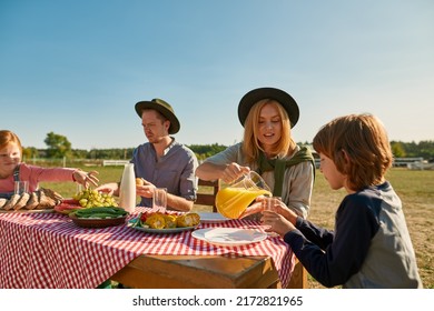 Young Caucasian Hipster Farming Family Having Lunch With Fresh Organic Products In Countryside Outdoors. Mother, Father, Daughter And Son Spending Time Together. Modern Farm Lifestyle. Sunny Day