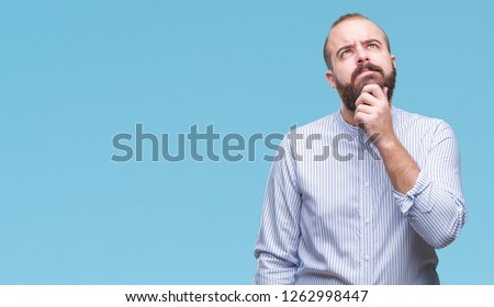 Young caucasian hipster man over isolated background with hand on chin thinking about question, pensive expression. Smiling with thoughtful face. Doubt concept.