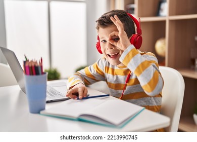 Young Caucasian Kid Doing Homework At Home Smiling Happy Doing Ok Sign With Hand On Eye Looking Through Fingers 