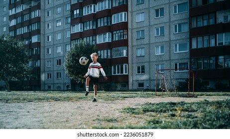 Young Caucasian Kid Playing with Ball in the Neighborhood. Boy Practicing Soccer Drills, Doing Kick-Ups. Teenager Dreaming of Becoming a Professional Football Player. Cold Desaturated Color Grading. - Powered by Shutterstock