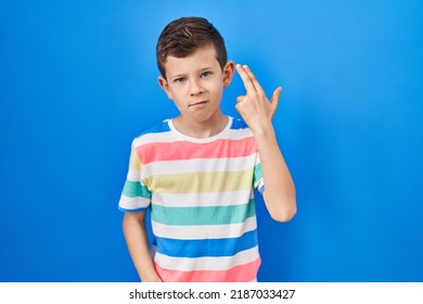 Young Caucasian Kid Standing Over Blue Background Shooting And Killing Oneself Pointing Hand And Fingers To Head Like Gun, Suicide Gesture. 