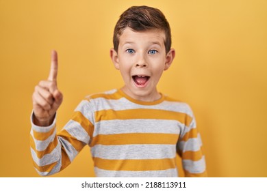 Young Caucasian Kid Standing Over Yellow Background Pointing Finger Up With Successful Idea. Exited And Happy. Number One. 