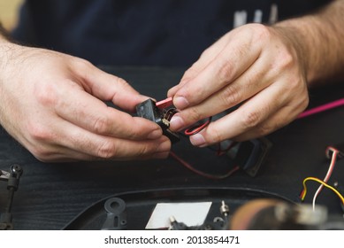 Young Caucasian male assembling toy RC car at home in the evening