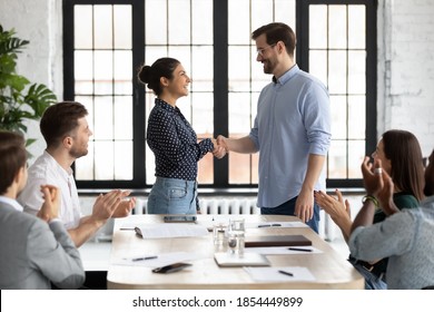 Young caucasian male ceo handshaking with indian female team member on briefing showing respect to her qualification, gratitude for help, recognition of her efforts in developing corporate business - Shutterstock ID 1854449899
