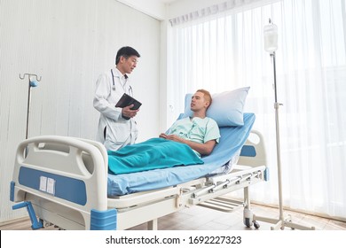 Young Caucasian Male Patient On Bed Talking To Doctor In Hospital Room, Health Care And Insurance Concept.