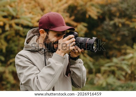 Young Caucasian Male Photographer Taking Picture in the autumn park
