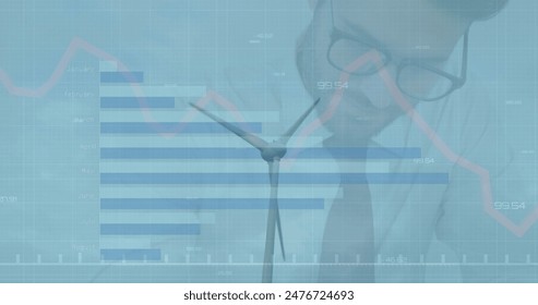 Young Caucasian male professional looking at graph on a transparent screen. Wind turbine and financial data overlay suggest focus on renewable energy - Powered by Shutterstock