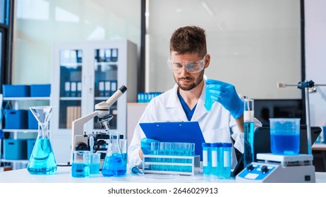 Young Caucasian male scientist works in laboratory, analyzing chemical samples with glassware and microscope. research tools, experiments, data interpretation, pharmaceutical development.
