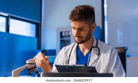 Young Caucasian male scientist works in laboratory, analyzing chemical samples with glassware and microscope. research tools, experiments, data interpretation, pharmaceutical development.