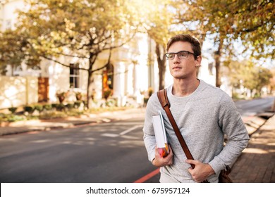 Young Caucasian Male Student With Book Outside On The Road. Handsome Young Man Going To College.