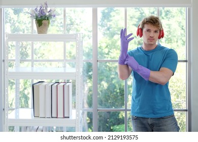 Young Caucasian male Wearing violet rubber gloves for clean of housework and relaxing for listening to music with red headphone. Lifestyle of Familyman on Holiday Concept. - Powered by Shutterstock