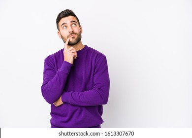 Young caucasian man against a white background isolated looking sideways with doubtful and skeptical expression.