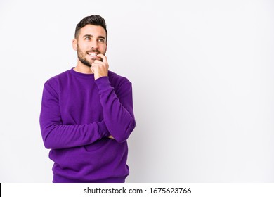 Young caucasian man against a white background isolated relaxed thinking about something looking at a copy space.