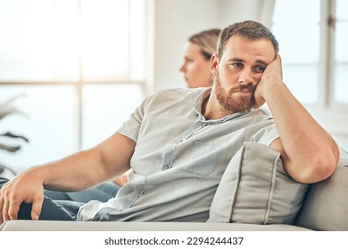 Young caucasian man with a beard looking unhappy and annoyed while sitting on the couch during an argument with his wife at home. Bored man sitting and thinking on the couch. - Shutterstock ID 2294244437