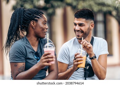 Young caucasian man and young black woman drinking a milkshake in the street - Powered by Shutterstock