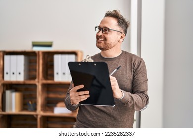 Young caucasian man business worker smiling confident writing on document at office