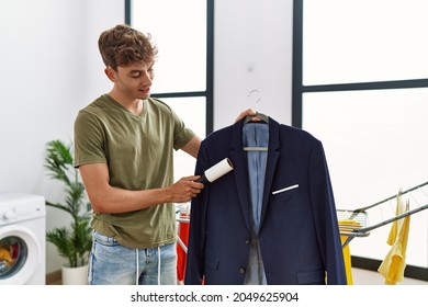 Young Caucasian Man Cleaning Jacket Using Pet Hair Roller At Laundry Room