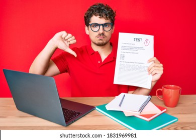 Young Caucasian Man With Curly Hair Sitting On The Table Showing Failed Exam With Angry Face, Negative Sign Showing Dislike With Thumbs Down, Rejection Concept 