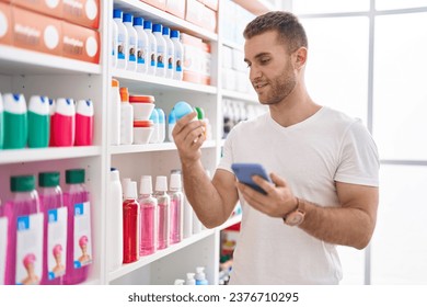 Joven cliente caucásico usando un desodorante para smartphones en la farmacia