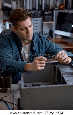 Young caucasian man disassembles broken computer. Computer service and repair concept. Computer disassembling in repair shop, workshop. Electronic development by professional technician