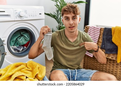 Young Caucasian Man Doing Laundry Holding Sock Pointing Finger To One Self Smiling Happy And Proud 