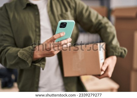 Young caucasian man ecommerce business worker using smartphone holding package at office