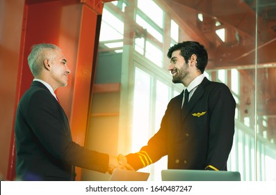 Young Caucasian Man Have Beard In Pilot Uniform Shaking Hands With Senior In Suit For Say Hello Together After Success Finishing Up A Meeting Collaboration,Two Business People Agreement,teamwork.