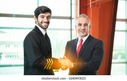 Young Caucasian Man Have Beard In Pilot Uniform Shaking Hands With Senior In Suit For Say Hello Together After Success Finishing Up A Meeting Collaboration,Two Business People Agreement,teamwork.