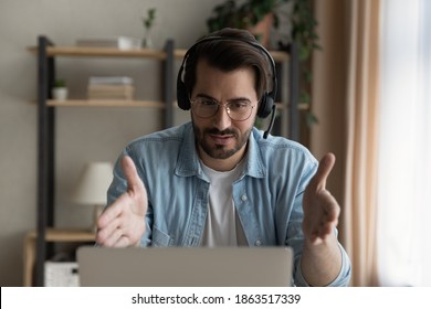 Young Caucasian Man In Headphones Work Online On Laptop Consult Client On Web. Serious Millennial Male In Earphones Have Webcam Digital Talk Or Video Call With Business Customer On Computer.