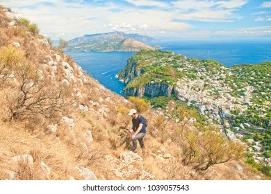 Young Caucasian Man Hiking Above The City Of Capri Using Smartphone Navigation On Sunny Summer Day, Italy