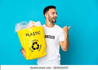 Young Caucasian Man Holding A Bag Full Of Plastic Bottles To Recycle Isolated On Blue Background Intending To Realizes The Solution While Lifting A Finger Up