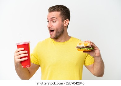 Young Caucasian Man Holding  Burger And Soda Isolated On White Background